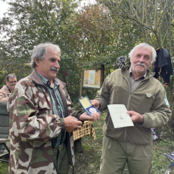 dvaja muži v poli s trofejou v rukách